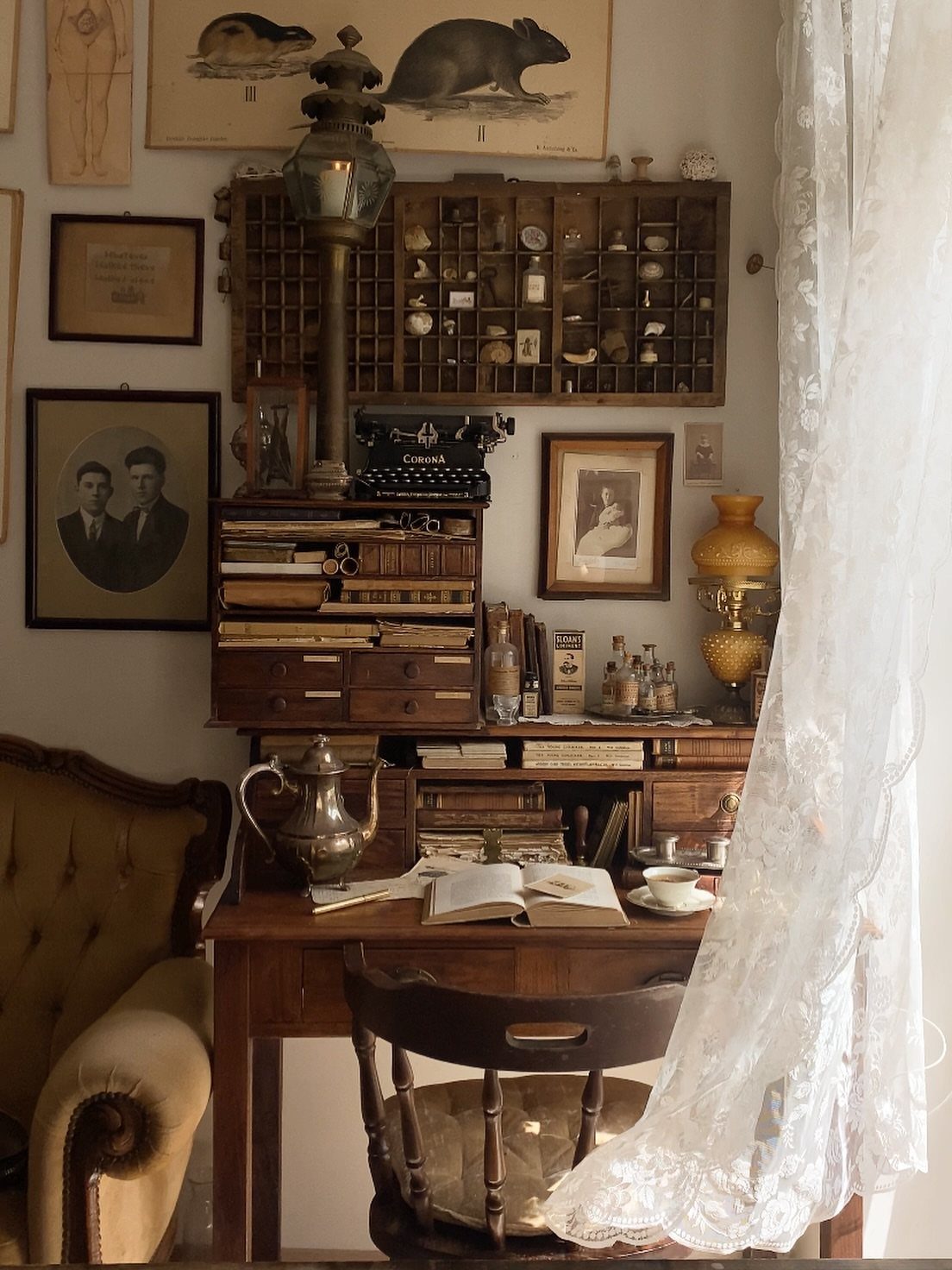 17 Antique Coffee Decor Ideas for Your Kitchen or Nook 18 Antique wooden desk with a silver coffee pot, typewriter, and vintage wall decor.
