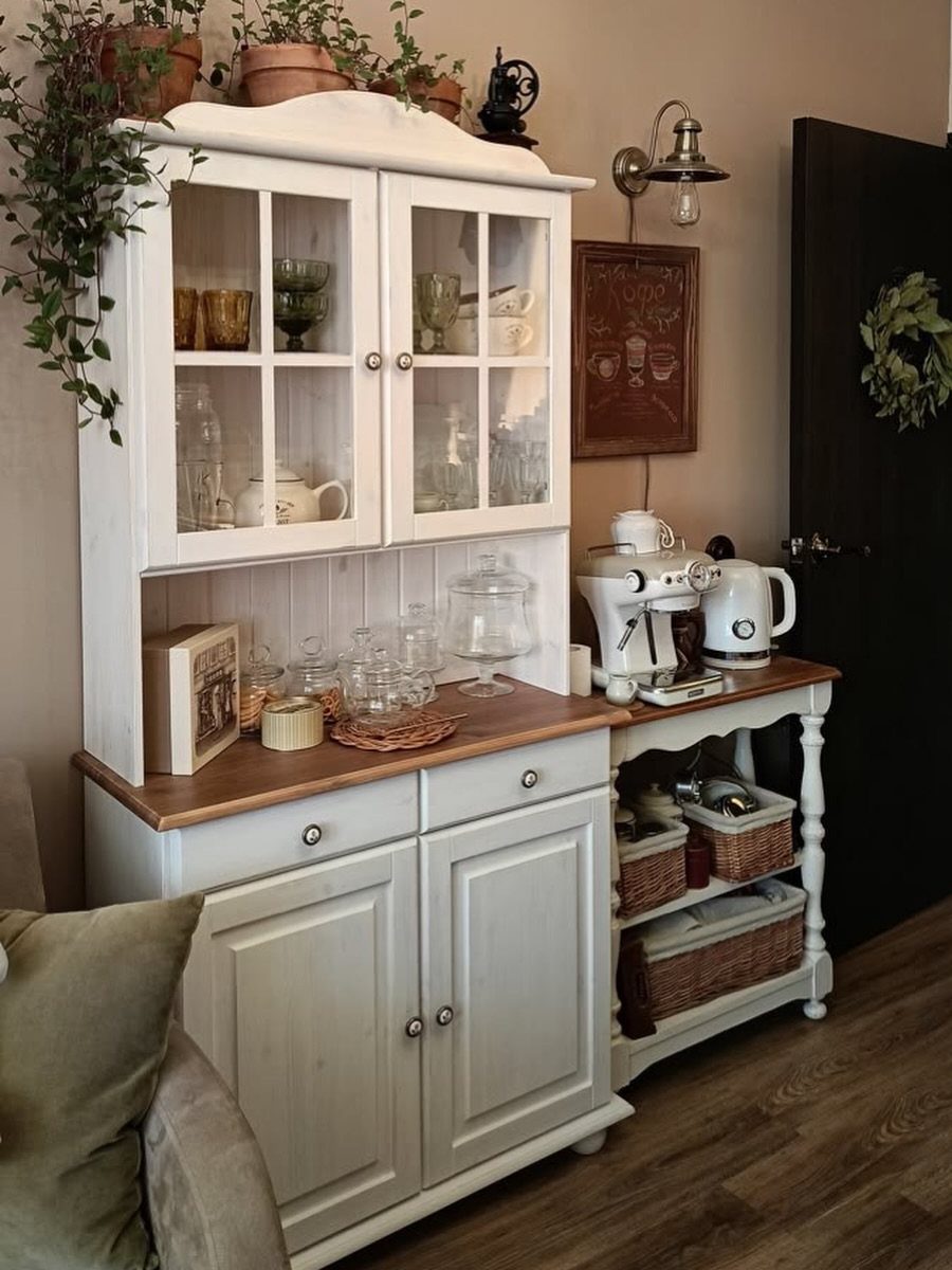 17 Antique Coffee Decor Ideas for Your Kitchen or Nook 3 White antique hutch coffee station with espresso machine, kettle, and glassware in a home.