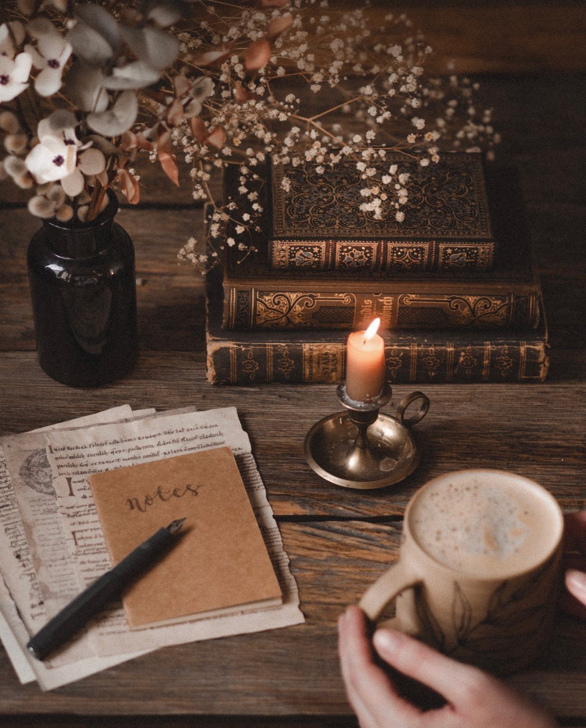 17 Antique Coffee Decor Ideas for Your Kitchen or Nook 16 Coffee cup, lit candle, and antique books on a rustic wooden table.