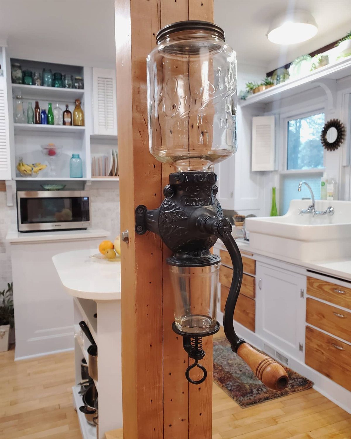 17 Antique Coffee Decor Ideas for Your Kitchen or Nook 6 Antique manual coffee grinder with glass hopper mounted on a wooden beam in kitchen.