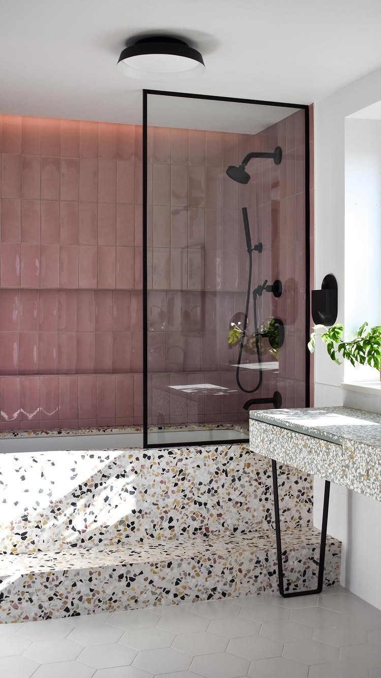 Terrazzo bathtub surround and countertop in a bathroom with pink wall tiles.