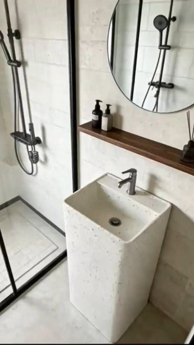 White terrazzo pedestal sink basin with chrome faucet in a modern minimalist bathroom.