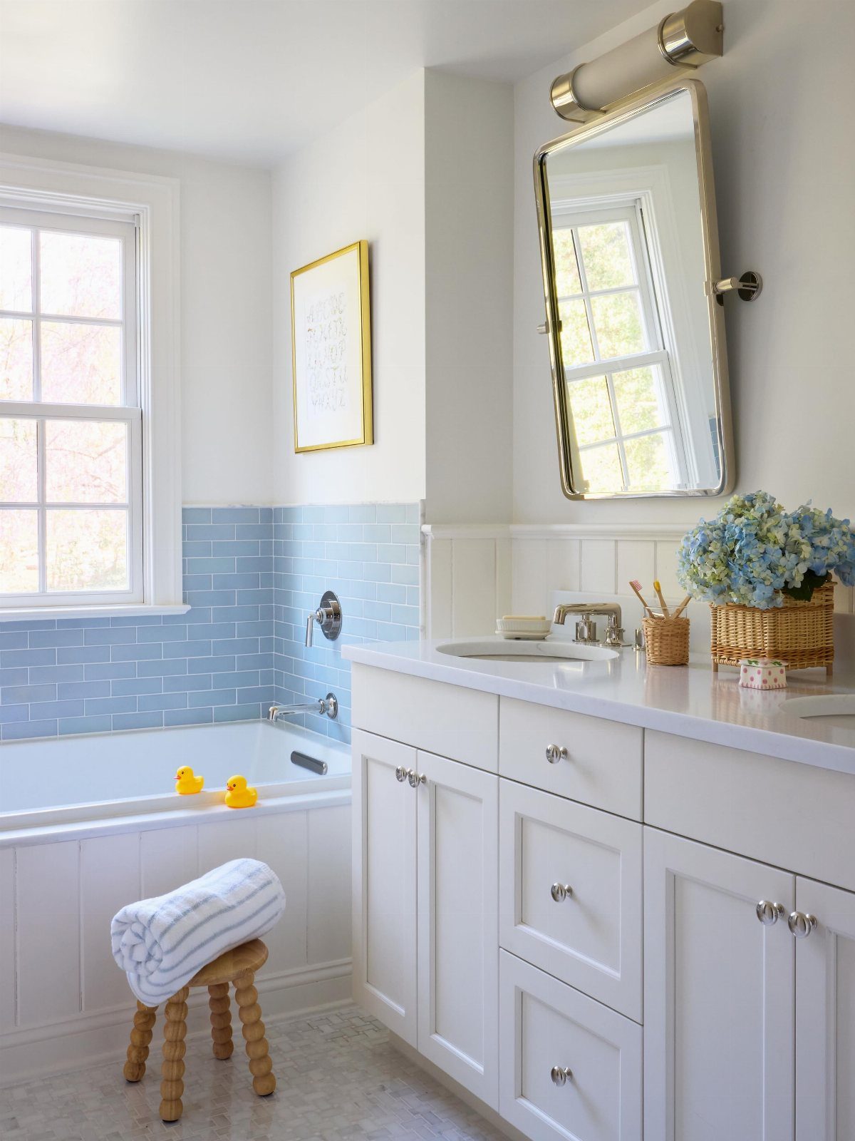 White bathroom vanity with sink next to a bathtub with light blue tiles.