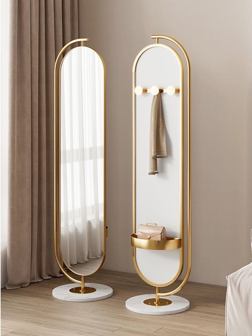 Gold framed oval full-length mirrors with white marble bases in a neutral room.
