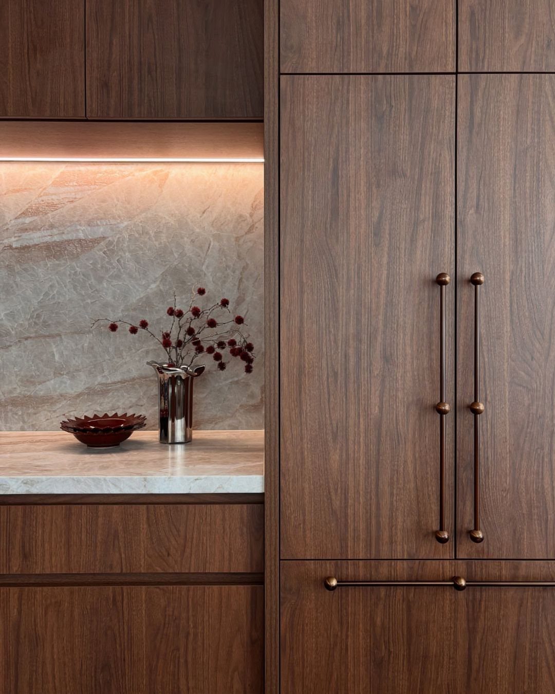 Walnut wood cabinets with white marble countertops and a matching marble backsplash.