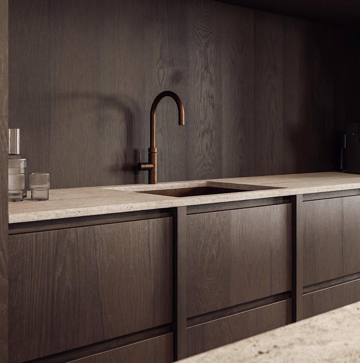 Dark walnut kitchen cabinets with light stone countertops and a bronze faucet.