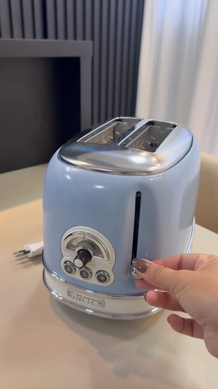 Blue Kitchen Appliances: 28 Ideas from Ranges to Kettles 6 Light blue retro toaster on a beige countertop with a hand pressing the lever.