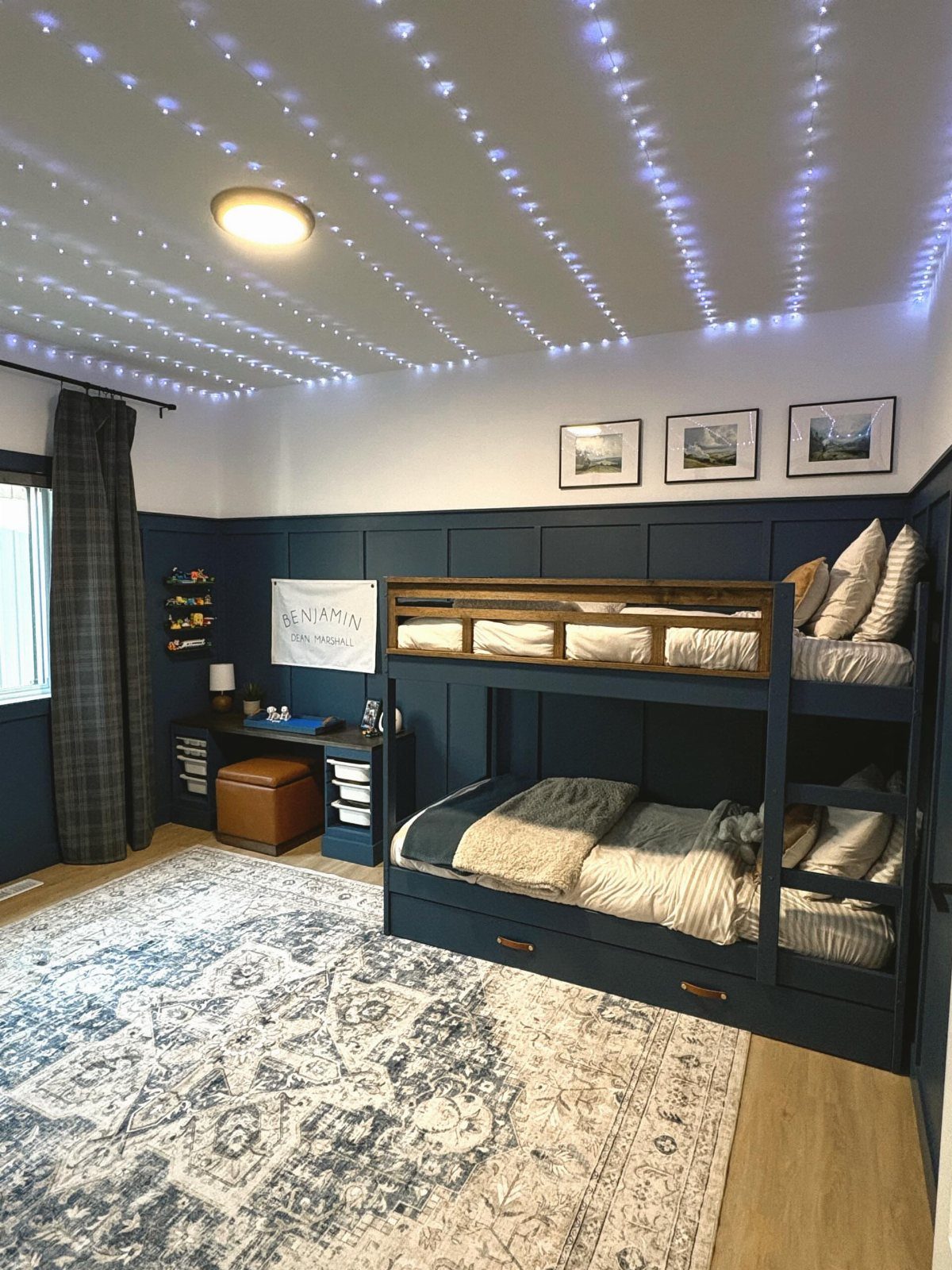 Navy-blue bunk bed with built-in storage drawers in a bedroom with starry ceiling lights.