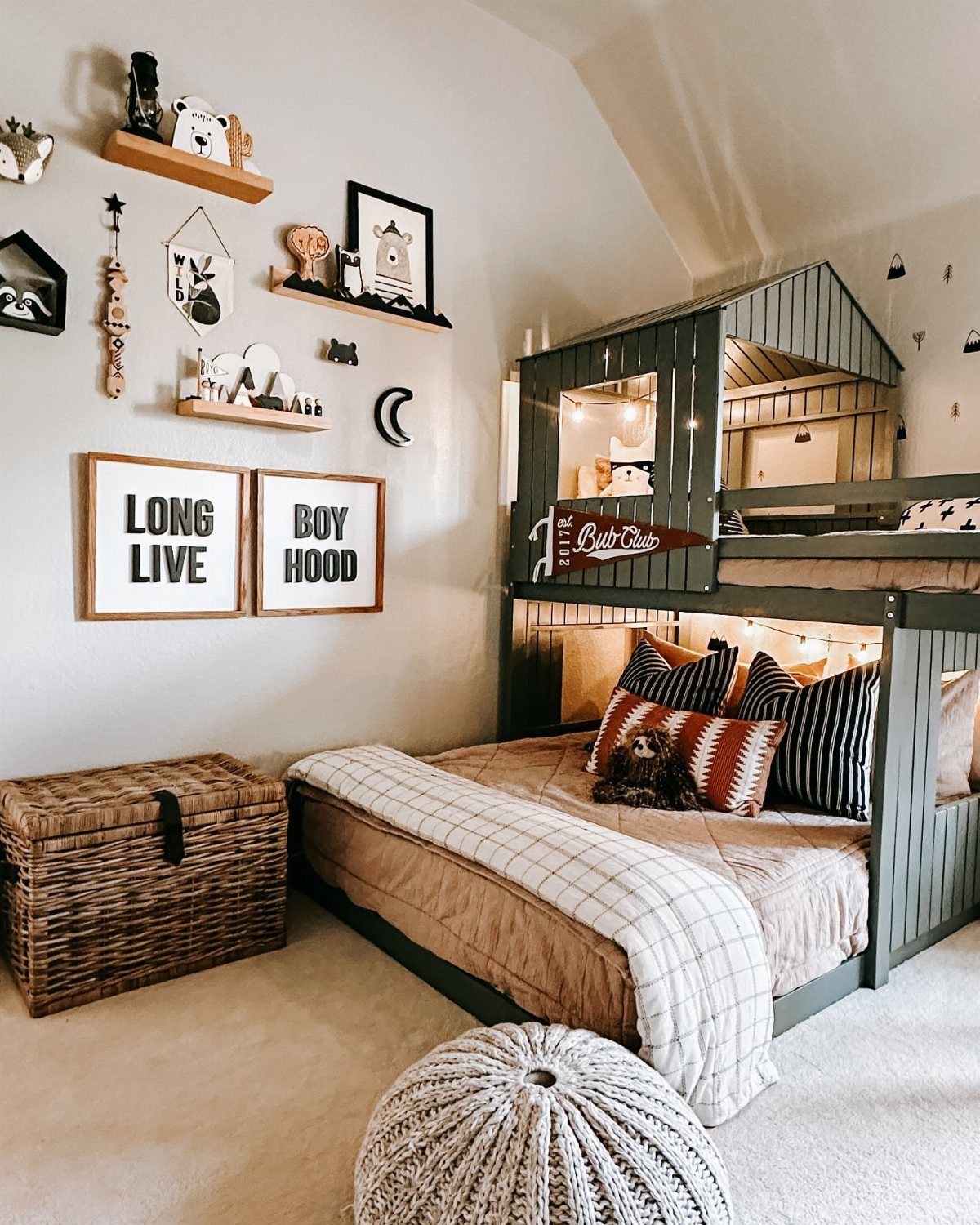 Dark green bunk bed with a peaked cabin roof in a decorated boy's bedroom.