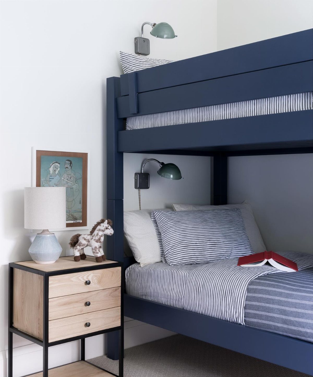Navy-blue bunk bed with striped bedding and a wooden nightstand in a bedroom.