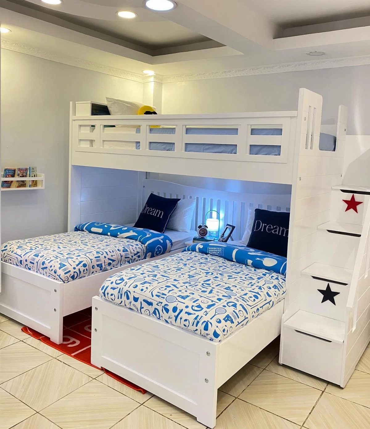White freestanding bunk bed with two bottom beds and a staircase in a bedroom.