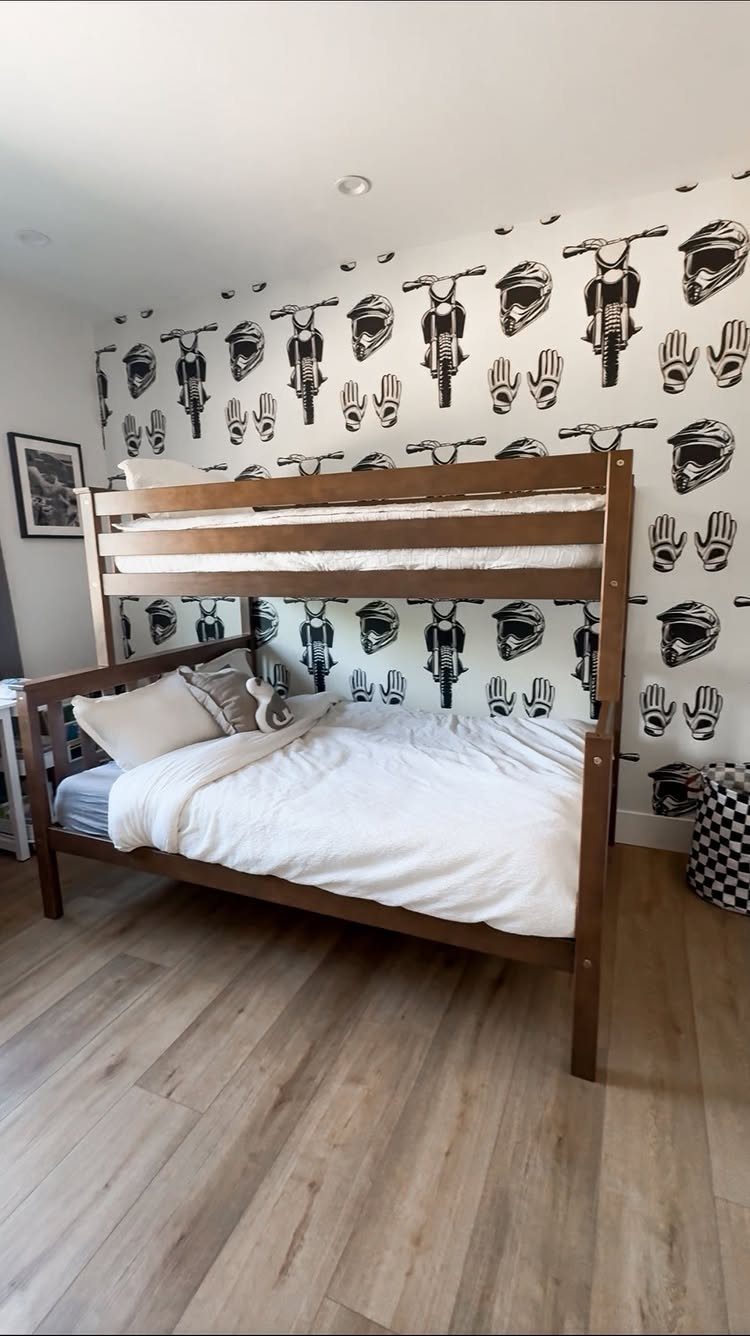 Wooden twin-over-full bunk bed against a motorcycle themed wallpaper background in a bedroom.
