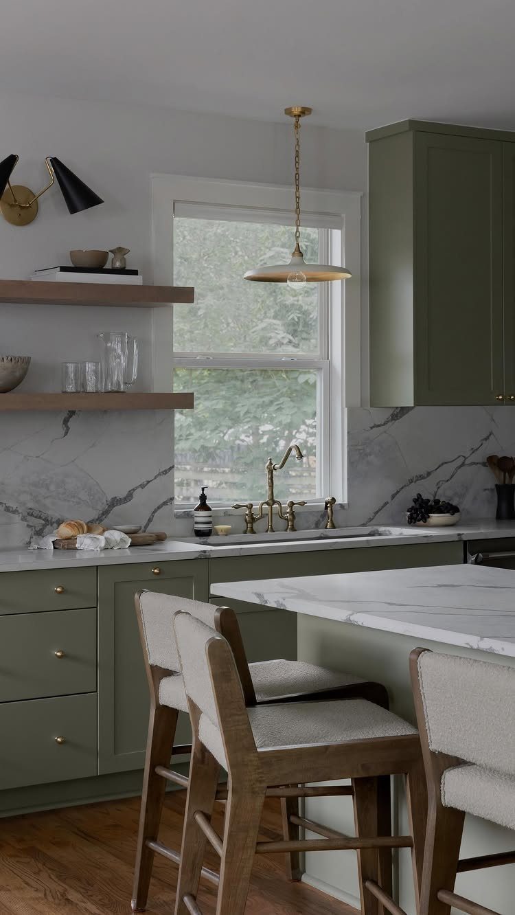 Cabinet Color Trends: 11 Ideas for Your Kitchen in 2026 3 Sage green kitchen cabinets with white marble countertops and light upholstered bar stools.