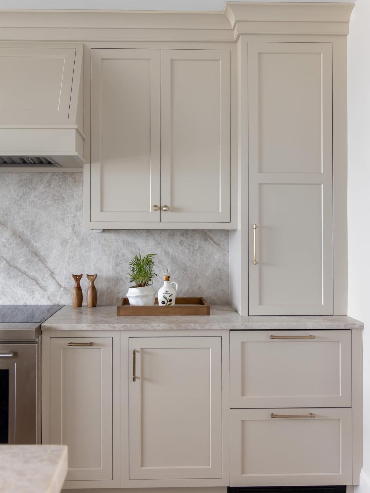 Cabinet Color Trends: 11 Ideas for Your Kitchen in 2026 11 Sand-toned shaker kitchen cabinets with gold hardware and a marble backsplash.