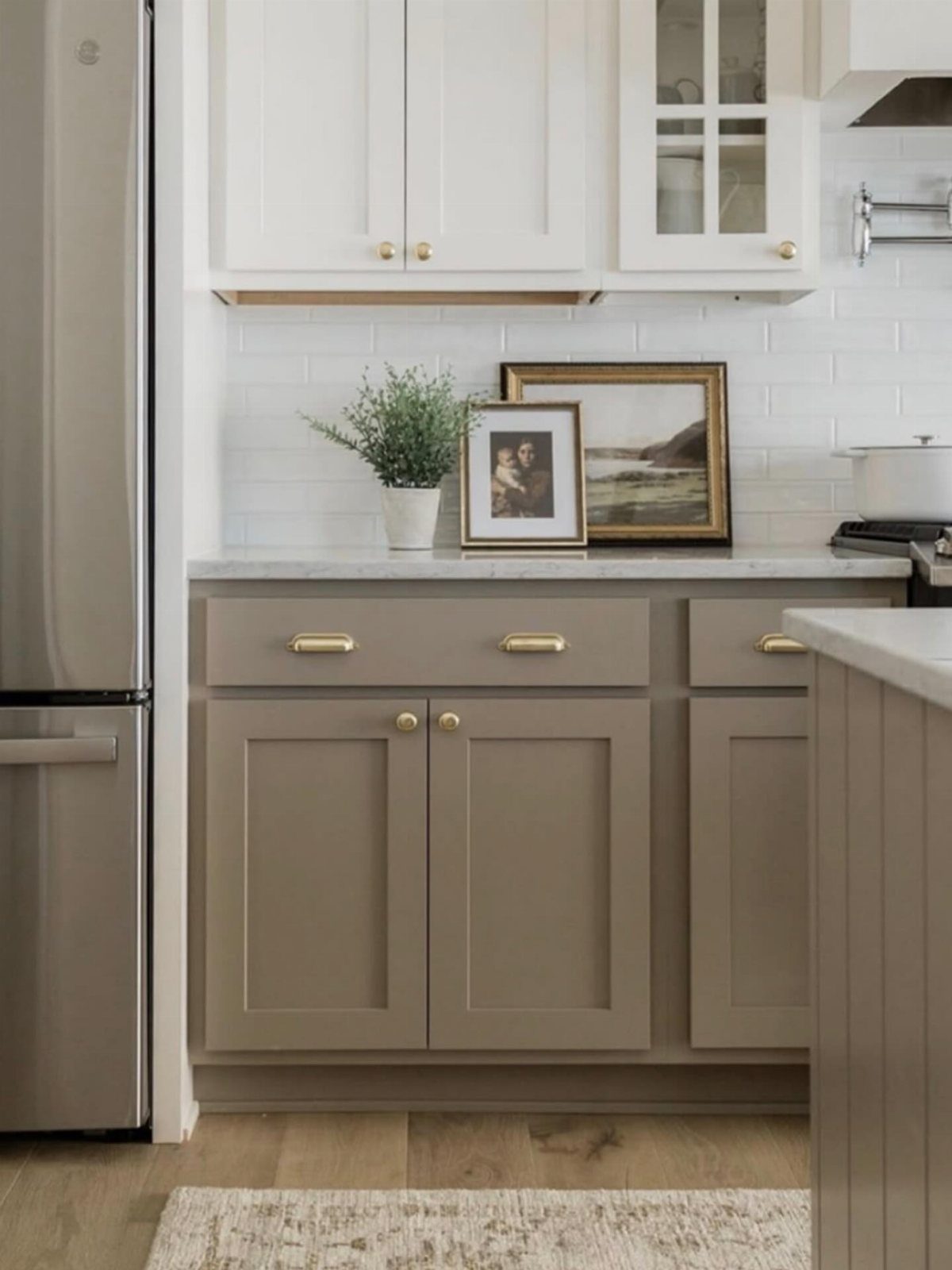 Cabinet Color Trends: 11 Ideas for Your Kitchen in 2026 5 Two-tone kitchen cabinets with white upper units and taupe lower units and gold hardware.