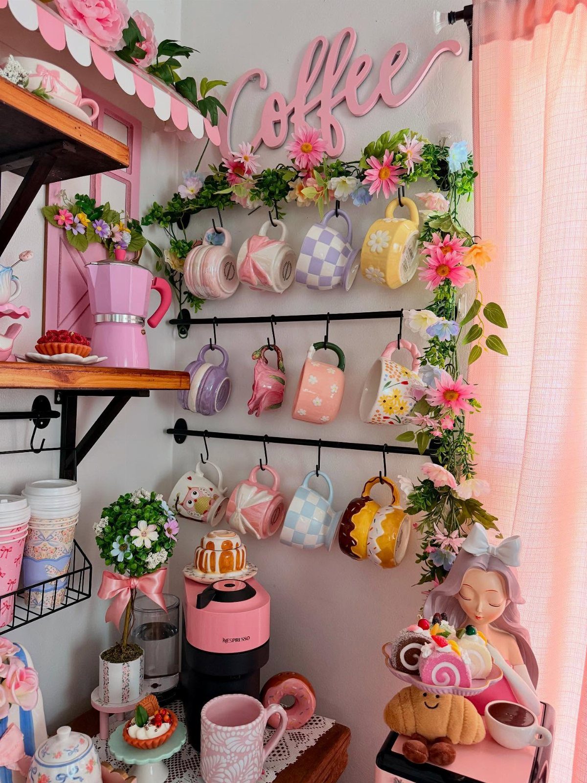 Pink coffee station with colorful hanging mugs, floral accents, and a pink coffee maker.