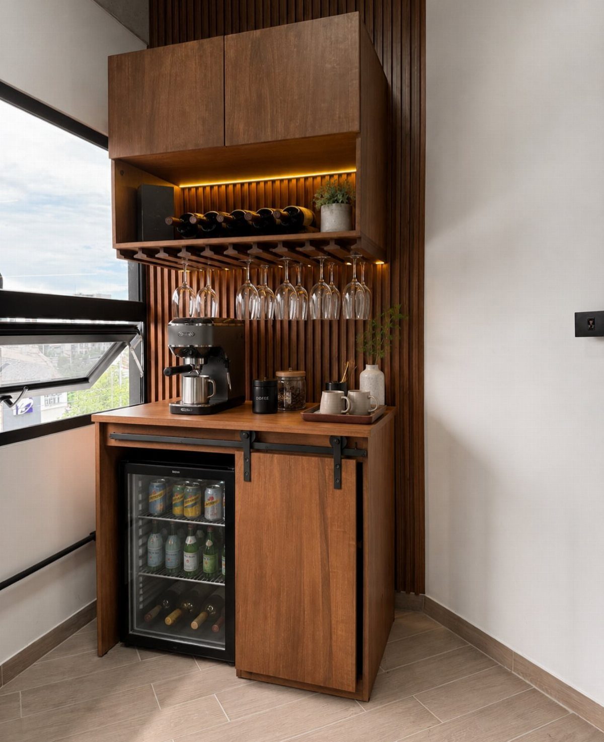 Wooden coffee and wine bar with espresso machine, wine glasses, and beverage fridge.