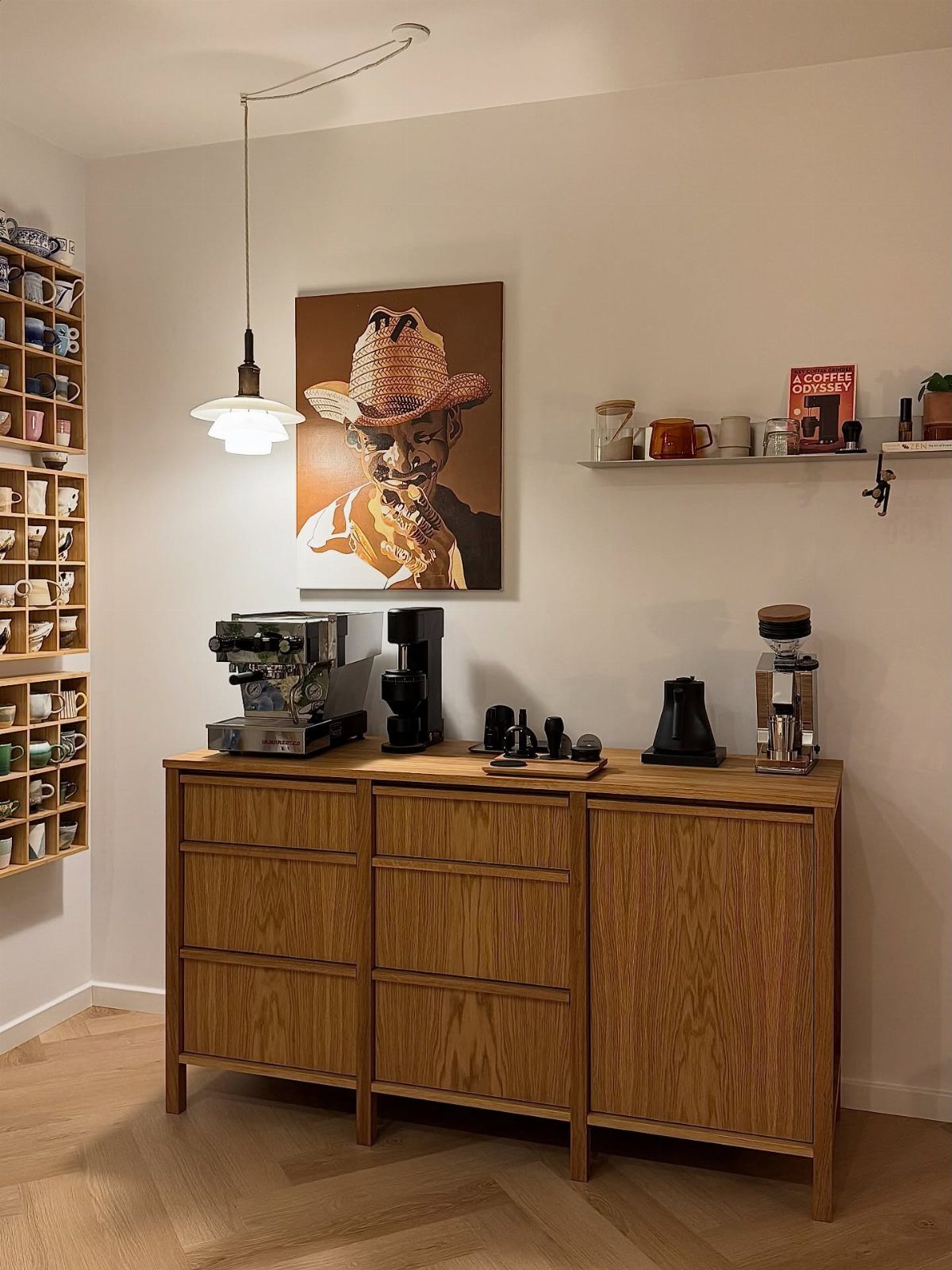 Wooden sideboard coffee bar with espresso machine and art on a white wall