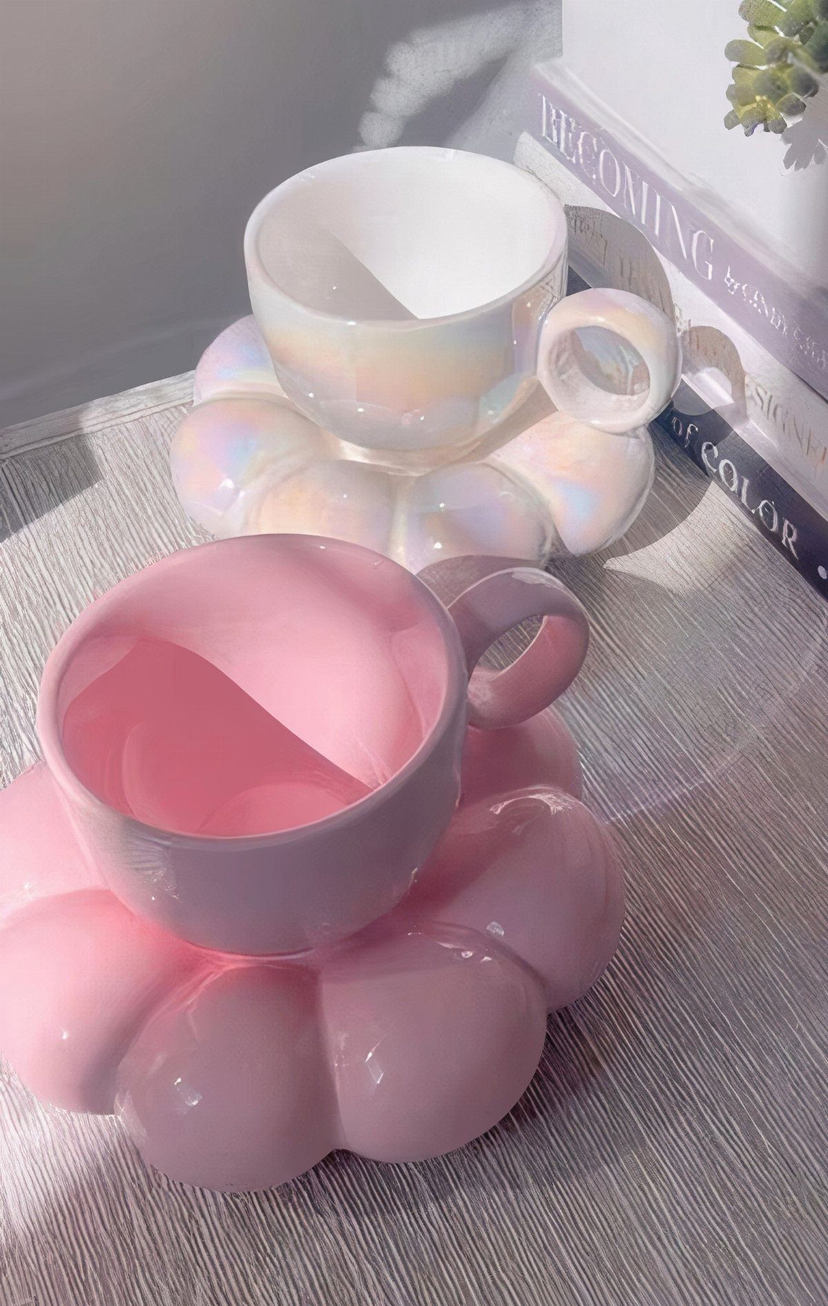Pink and iridescent mugs resting on chunky bubble-shaped saucers on a table.