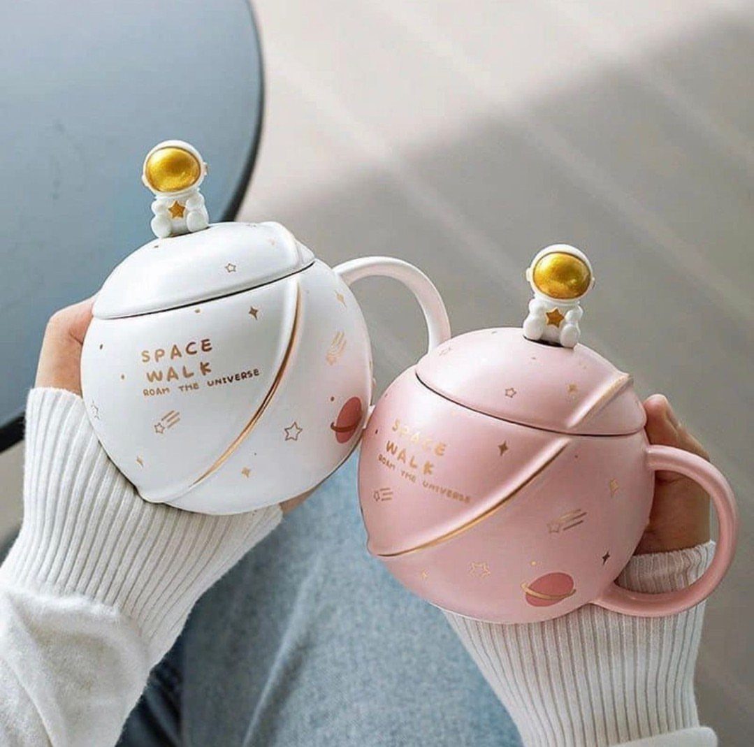 Two spherical space-themed mugs with astronaut lids in white and pink colors.