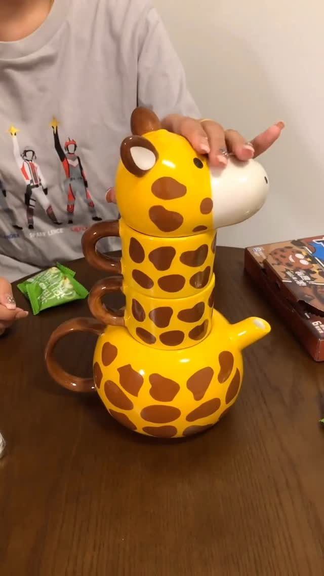 Yellow giraffe patterned teapot and stacked mugs with a giraffe head lid