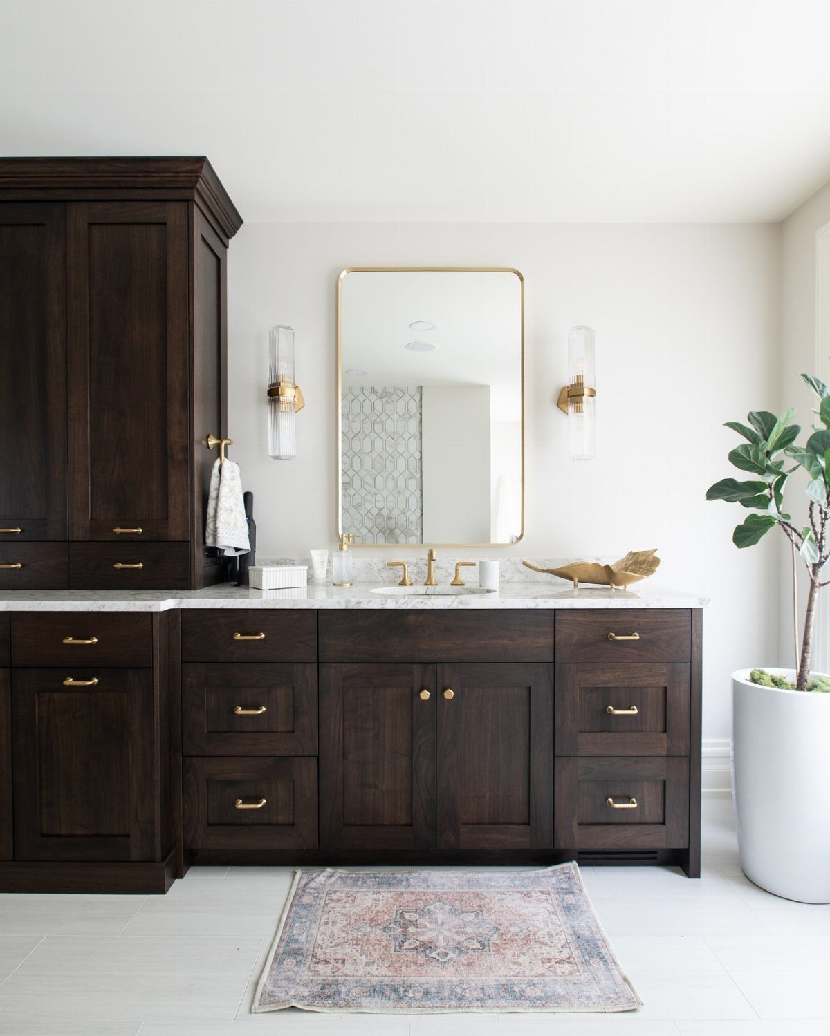 Dark brown bathroom cabinets with gold hardware and a white marble countertop.