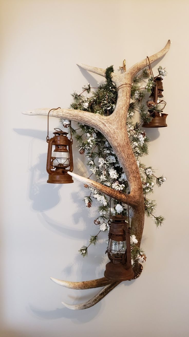 Deer antlers mounted on a wall decorated with greenery and rustic hanging lanterns