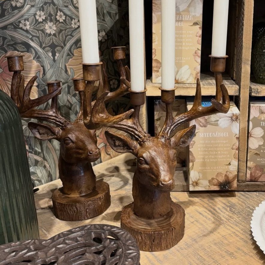Wooden deer head candle holders with white taper candles on a rustic wooden surface