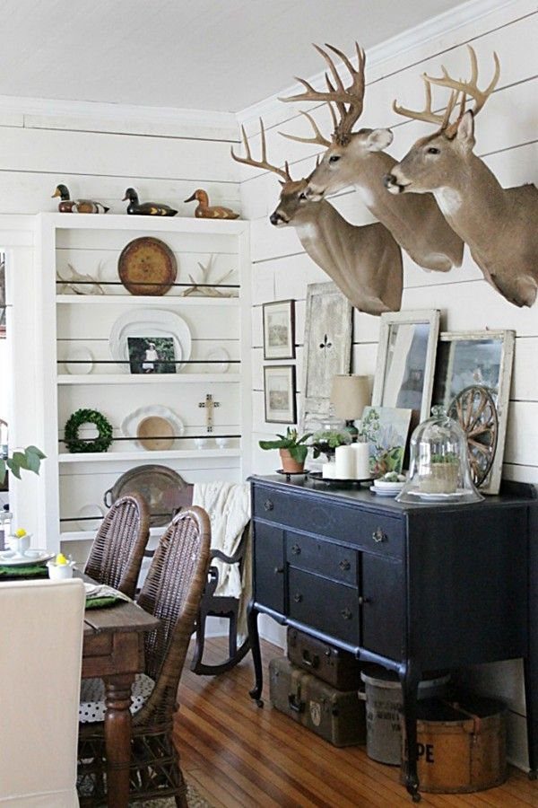 Three deer head mounts on a white shiplap wall above a blue sideboard.