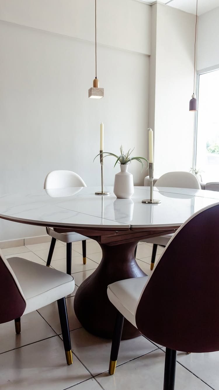 Oval white dining table with a dark sculptural base and modern chairs.