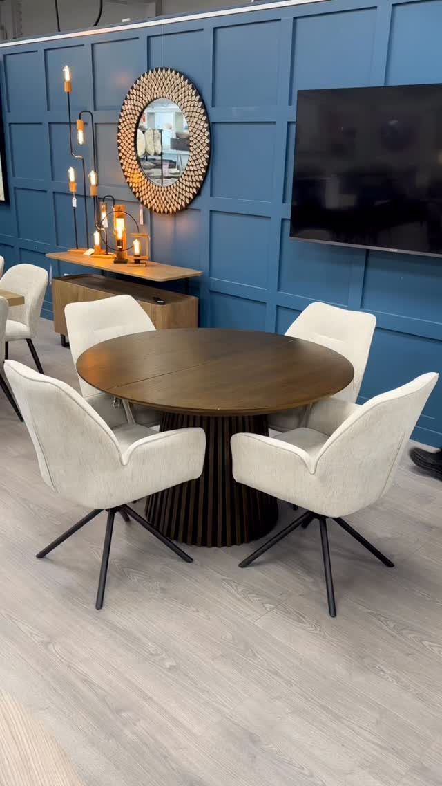 Round dark wood dining table with fluted base and four white modern chairs.