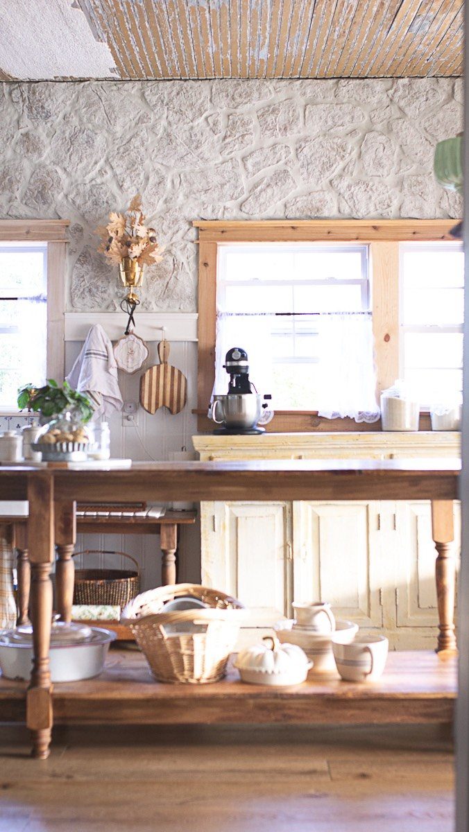 Farmhouse Kitchen Island Ideas: 14 Styles with Photos 12 Rustic wooden kitchen island with open shelving and a stone wall background
