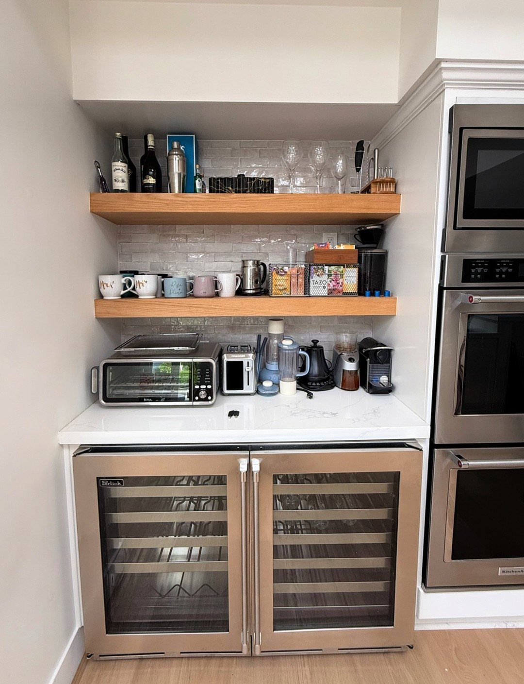 16 Home Coffee Stand Ideas to Fit Any Space 17 Built-in beverage station with wooden shelves, white tile backsplash, and a wine cooler.