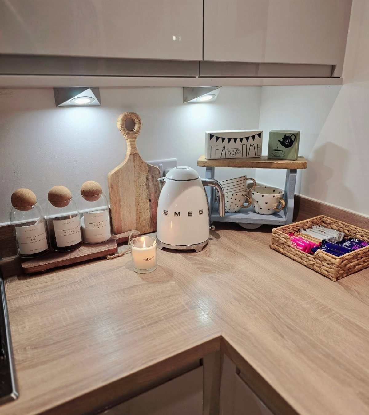 16 Home Coffee Stand Ideas to Fit Any Space 11 White electric kettle and tea accessories on a light wood kitchen countertop station.