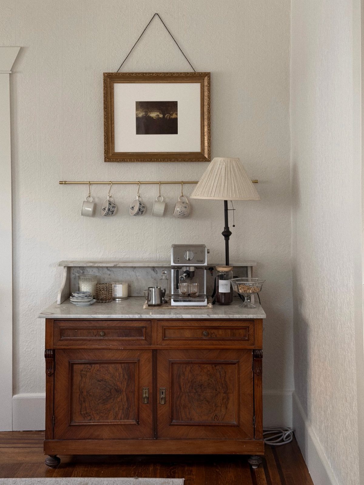16 Home Coffee Stand Ideas to Fit Any Space 5 Vintage wooden cabinet coffee station with marble top, espresso machine, and hanging mugs.