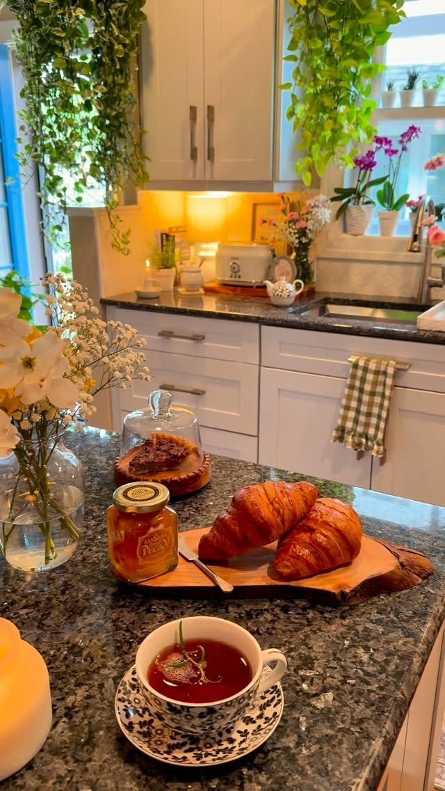 20 Home Kitchen Decor Ideas to Refresh Your Space 3 Kitchen countertop with breakfast and tea, featuring trailing green plants on white cabinets.