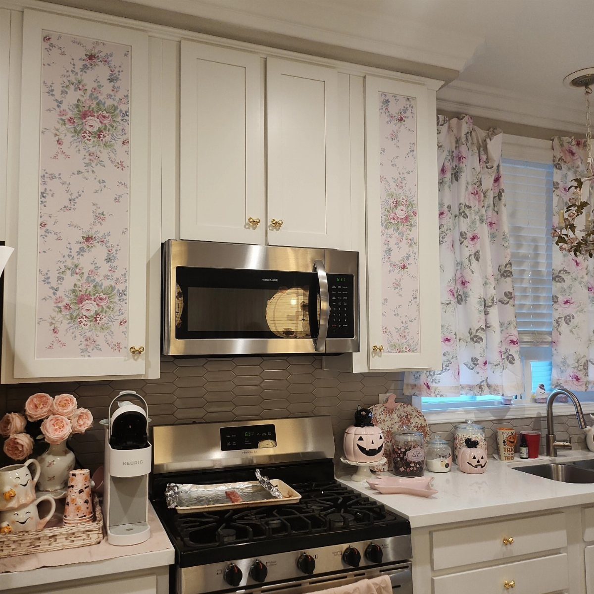 20 Home Kitchen Decor Ideas to Refresh Your Space 7 White kitchen cabinets with floral wallpaper inserts and matching floral window curtains.