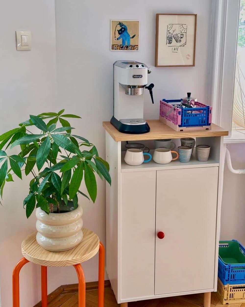 White EKET coffee cabinet with espresso machine, mugs, and a potted plant.