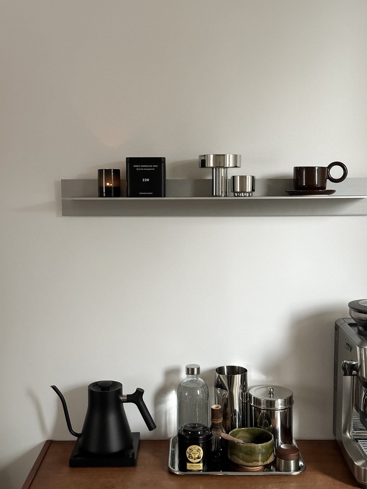 Coffee station with a black gooseneck kettle and a grey floating shelf above.