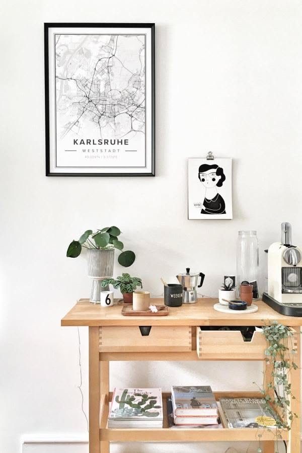 Light wood kitchen cart coffee station with espresso machine and framed wall art.