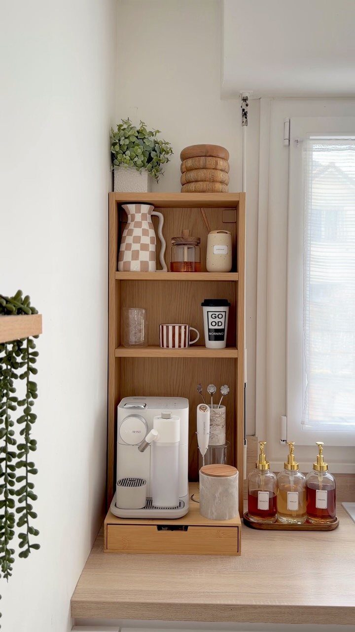 Light wood shelving unit coffee station with white espresso machine and mugs.