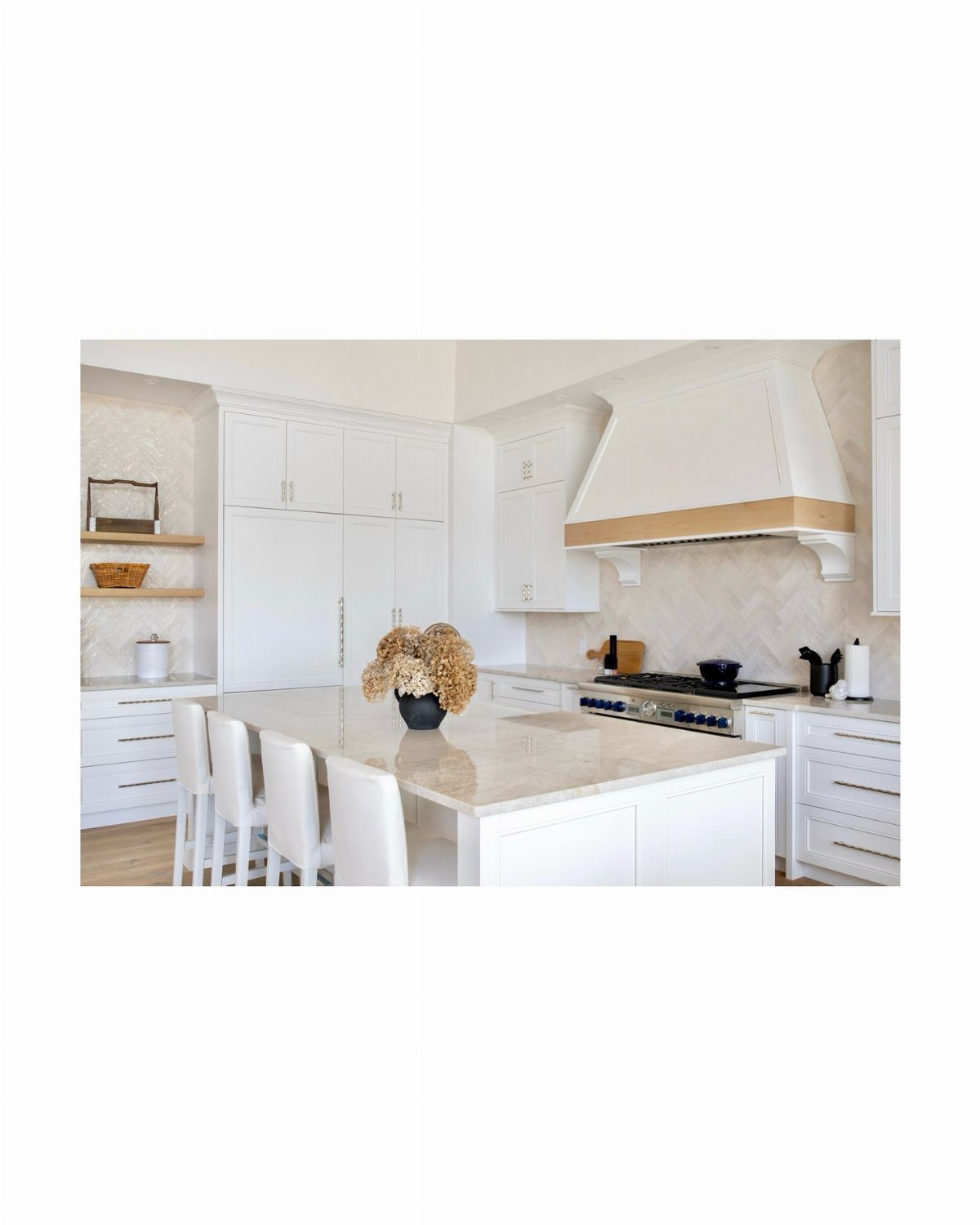White kitchen with a large island and a geometric patterned tile backsplash.