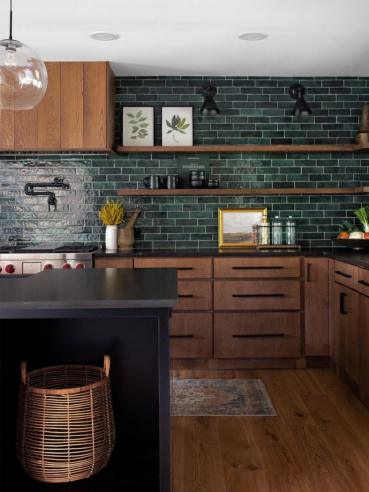 Dark green tiled kitchen wall with wooden cabinets and open shelving.