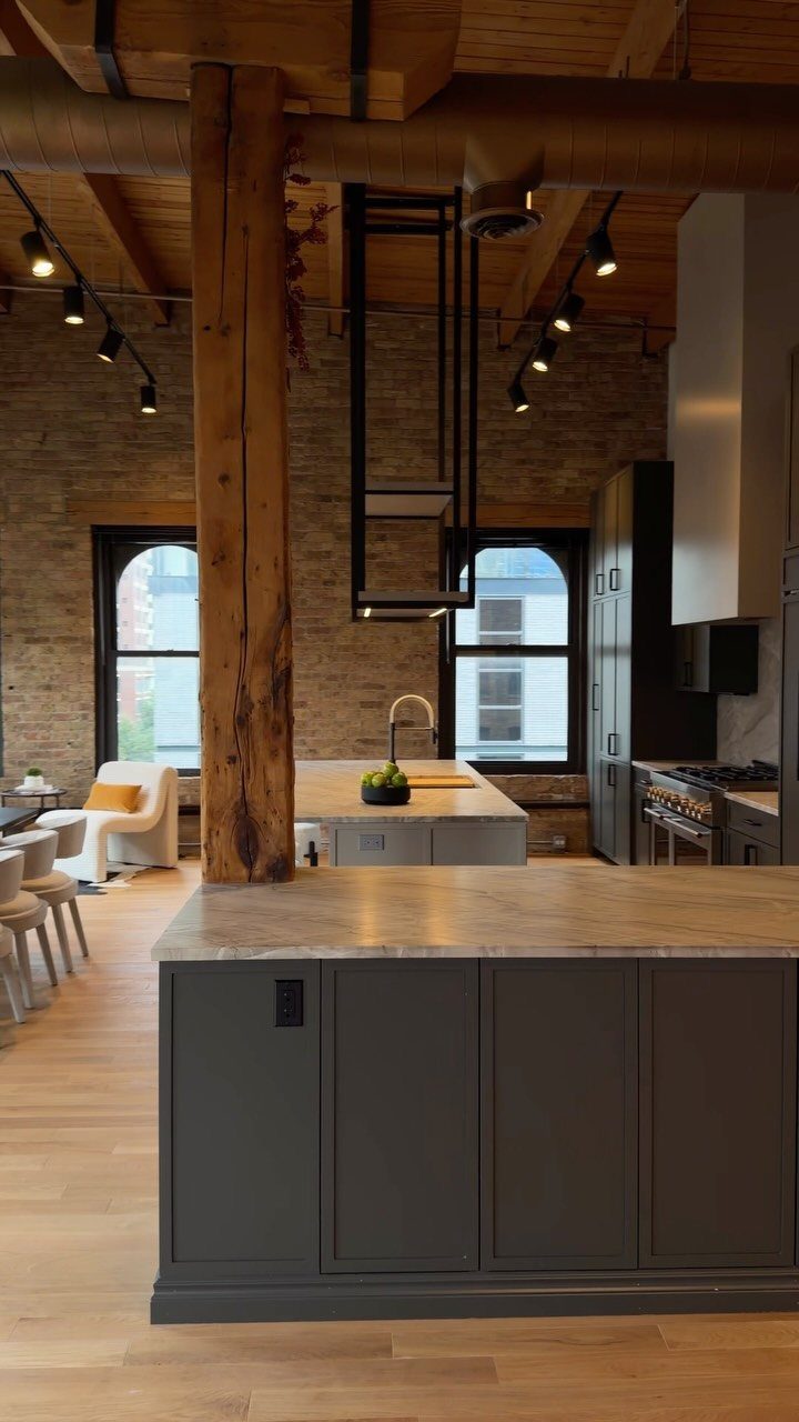 Modern kitchen with a grey island and a textured exposed brick wall background.