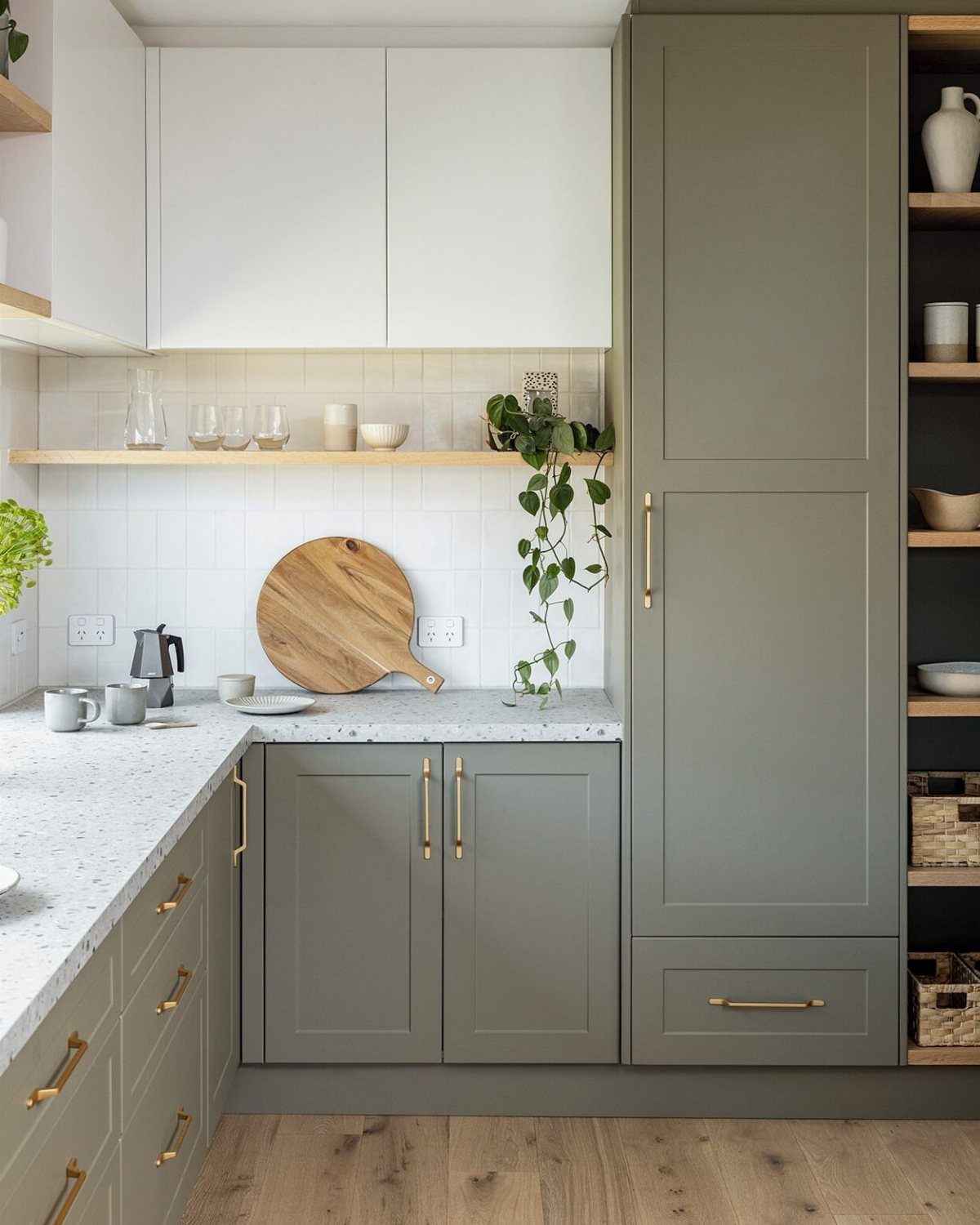 Modern kitchen with white upper cabinets and sage green lower cabinetry and gold hardware