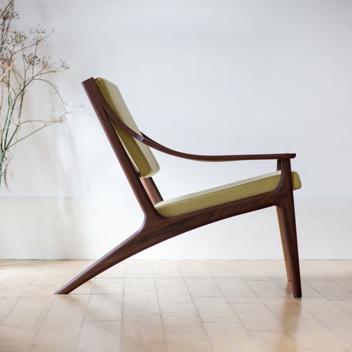Interior Design Minimalist: 15 Ideas for Clean, Simple Spaces 3 Mid-century modern wooden lounge chair with light green upholstery against a white wall.