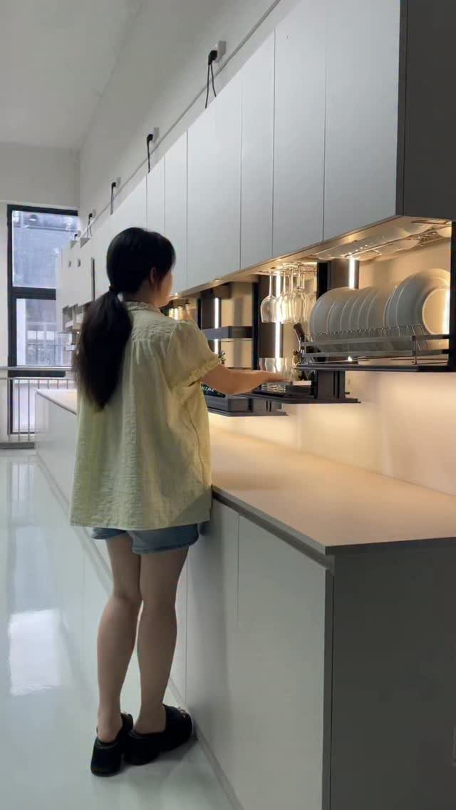 Interior Design Minimalist: 15 Ideas for Clean, Simple Spaces 7 Woman accessing a pull-down storage shelf inside a minimalist white kitchen cabinet.