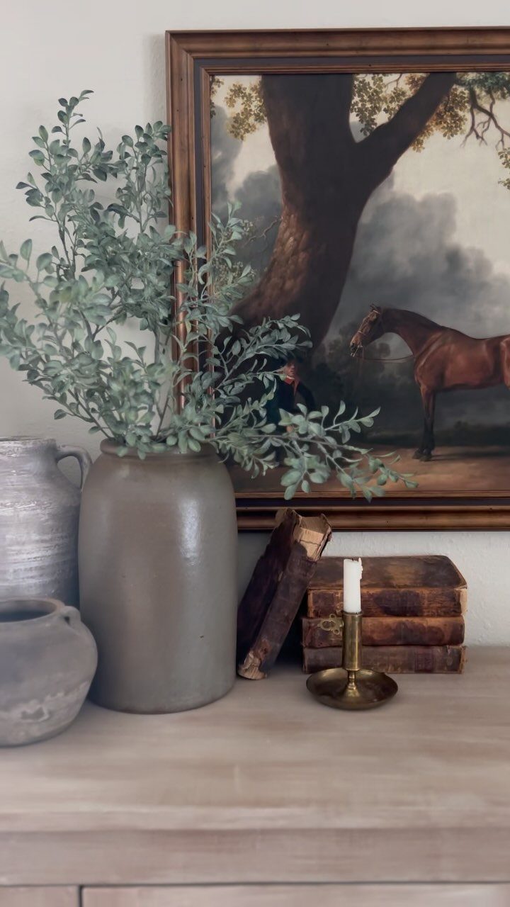 Interior Design Minimalist: 15 Ideas for Clean, Simple Spaces 16 Wooden surface with ceramic vases, green foliage, old books, and a framed horse painting.