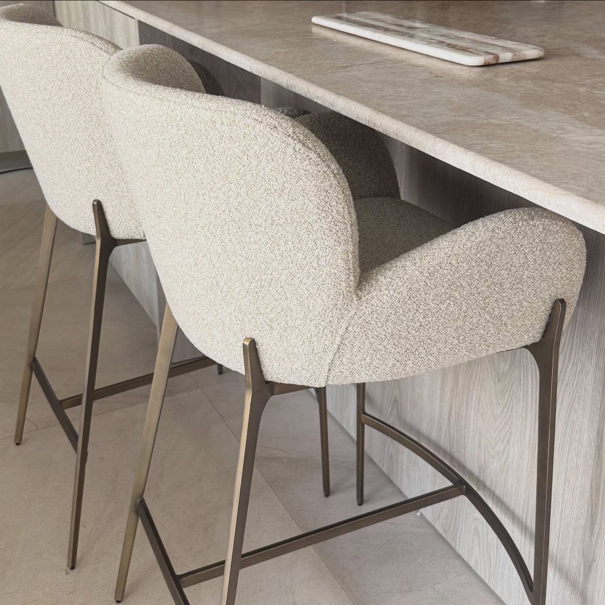 Interior Design Minimalist: 15 Ideas for Clean, Simple Spaces 13 Cream upholstered bar stools with bronze legs under a marble countertop in a minimalist room.