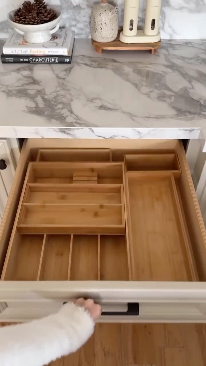 Bamboo cutlery tray organizing utensils inside an open white kitchen drawer.